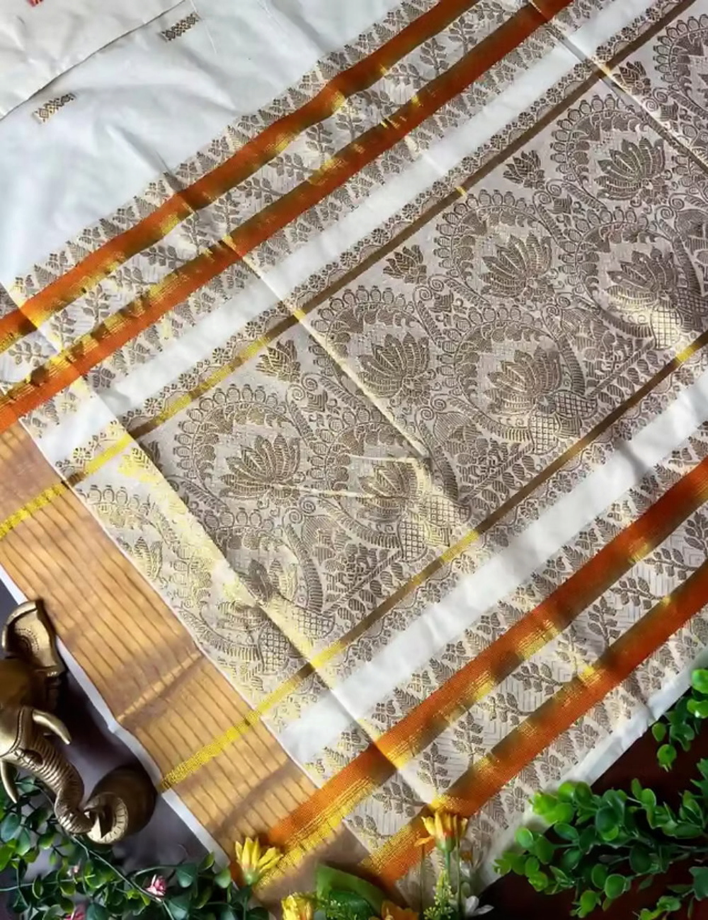House Of Paramya off-white cotton Kasavu saree featuring intricate golden lotus jacquard and a vibrant orange border.