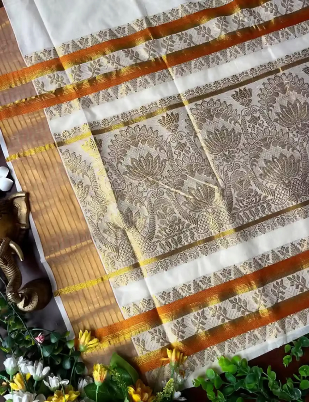 House Of Paramya off-white cotton Kasavu saree featuring golden lotus jacquard patterns and an orange contrast border.