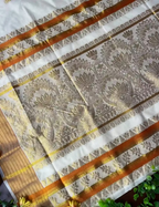 House Of Paramya off-white cotton Kasavu saree featuring golden lotus jacquard patterns and an orange contrast border.