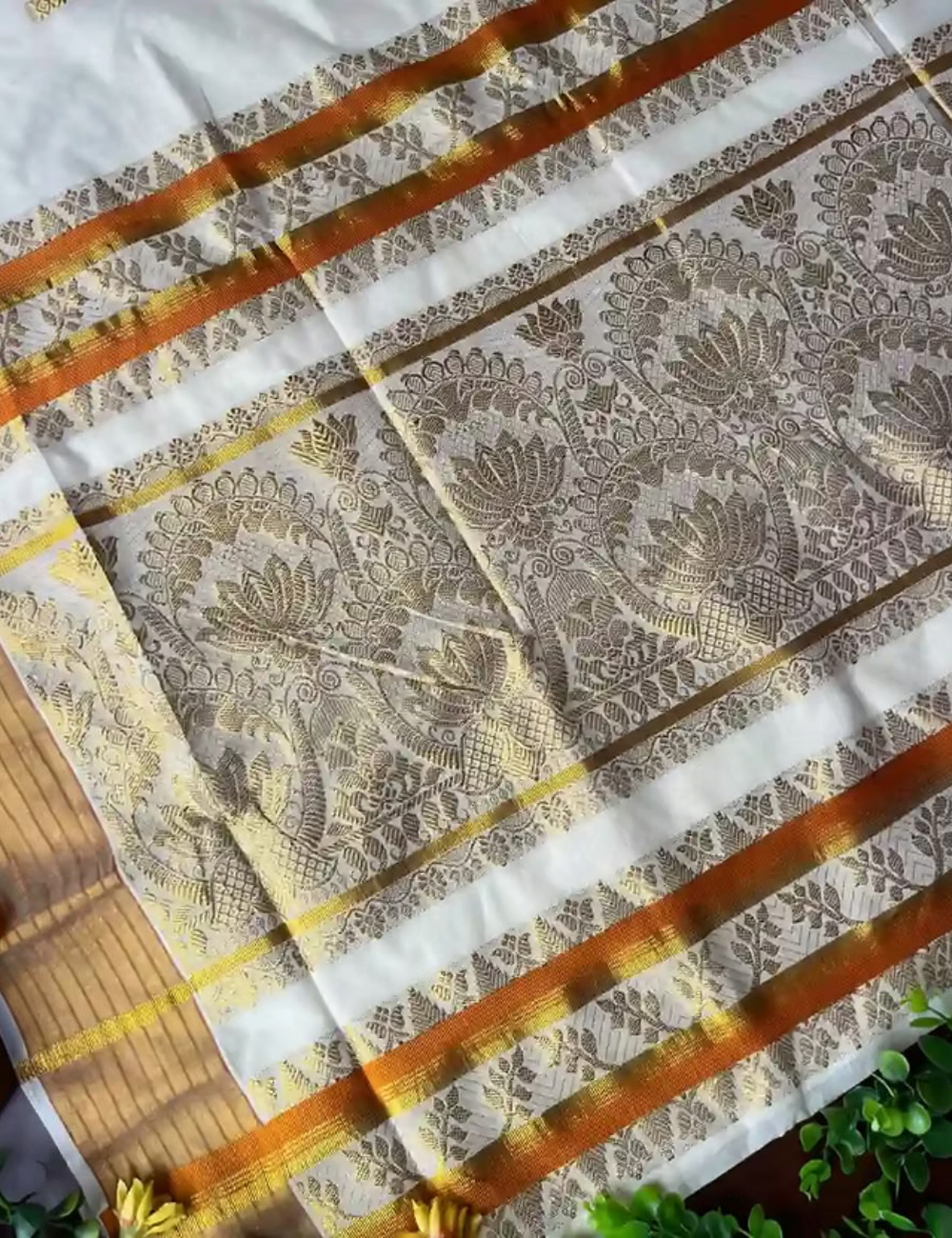 House Of Paramya off-white cotton Kasavu saree featuring golden lotus jacquard patterns and an orange contrast border.