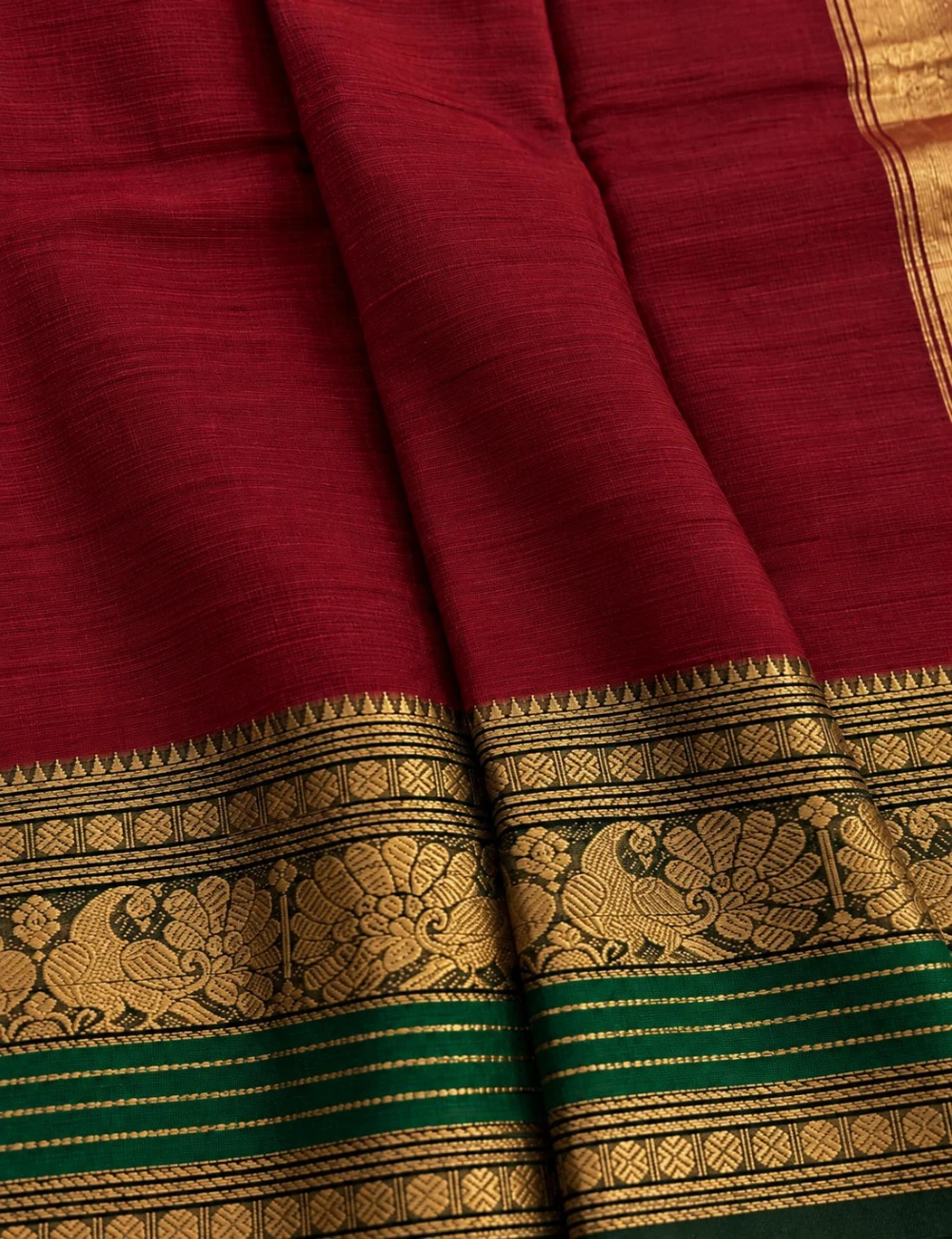 House Of Paramya maroon Chettinad cotton saree with a bottle green border featuring antique gold zari peacock motifs.
