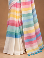 House Of Paramya white linen cotton saree featuring pastel rainbow stripes and a gold border with blue tassel ends.