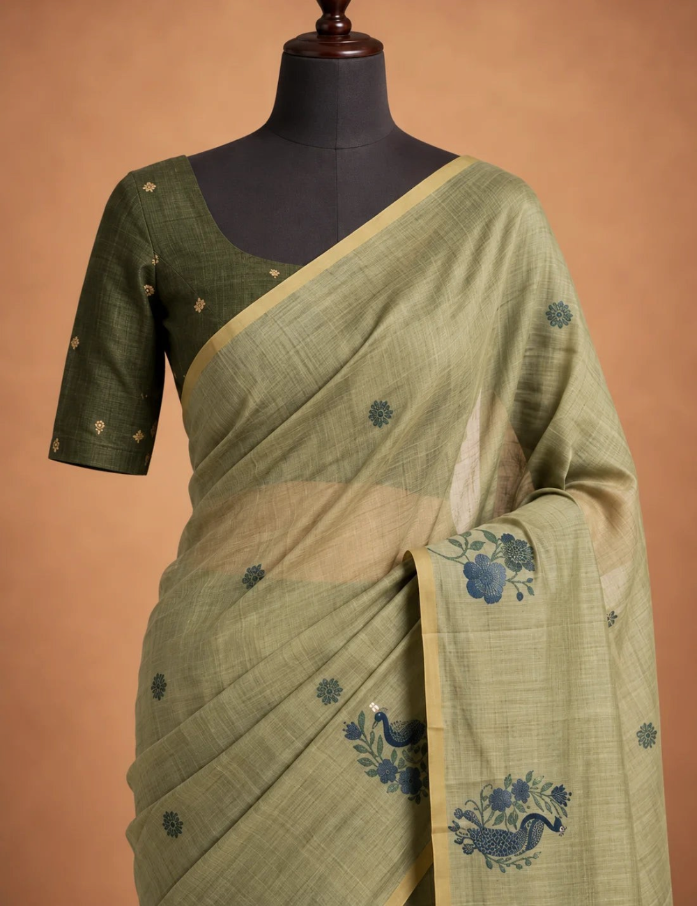 House Of Paramya olive green Munga cotton saree featuring blue woven peacock and floral motifs on a mannequin