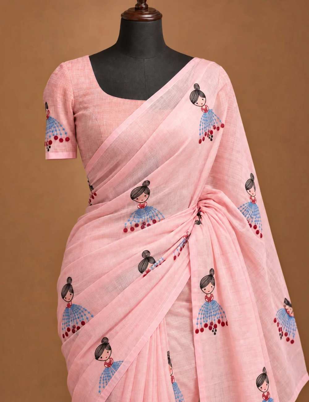 House Of Paramya powder pink linen cotton saree featuring a whimsical doll print and a delicate gold striped border.