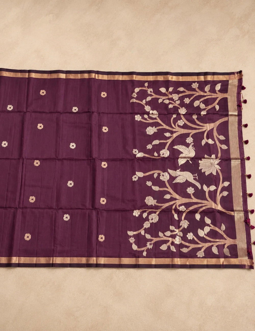 House Of Paramya plum raw tussar cotton saree featuring gold zari floral tree pallu and woven buttis with tassels.