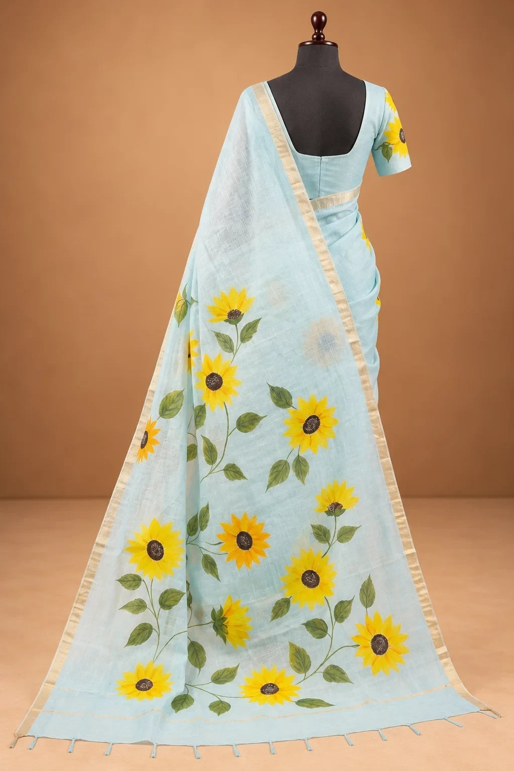 House Of Paramya powder blue linen cotton saree featuring vibrant sunflower prints and a delicate gold zari border.