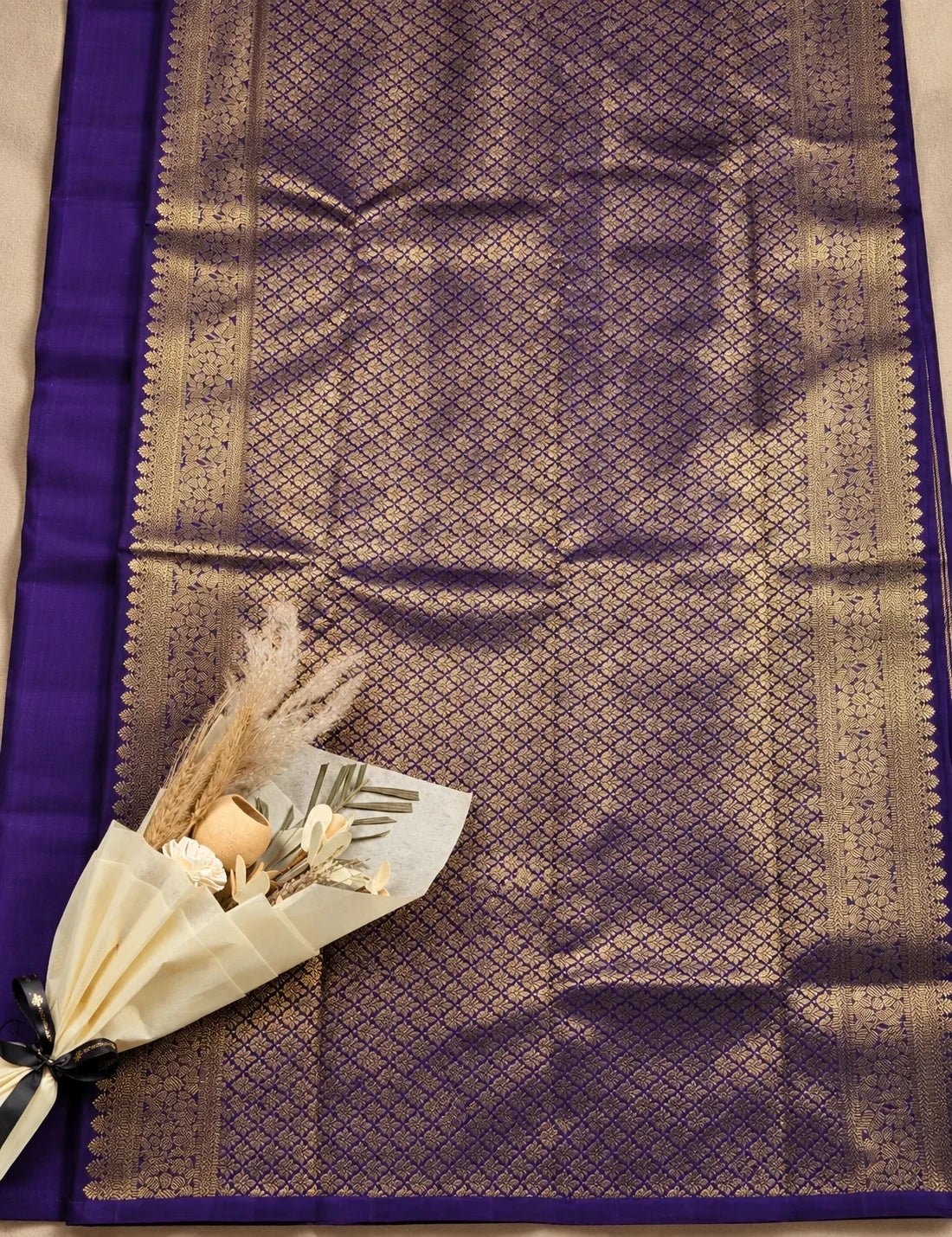 House Of Paramya dark purple Kanchipuram silk saree with intricate silver zari weaving and a decorative floral accent.